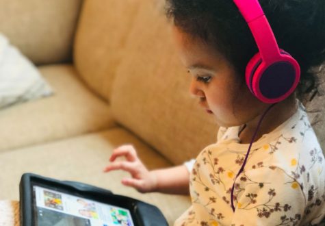 Young girl on sofa looking at a tablet, wearing headphones