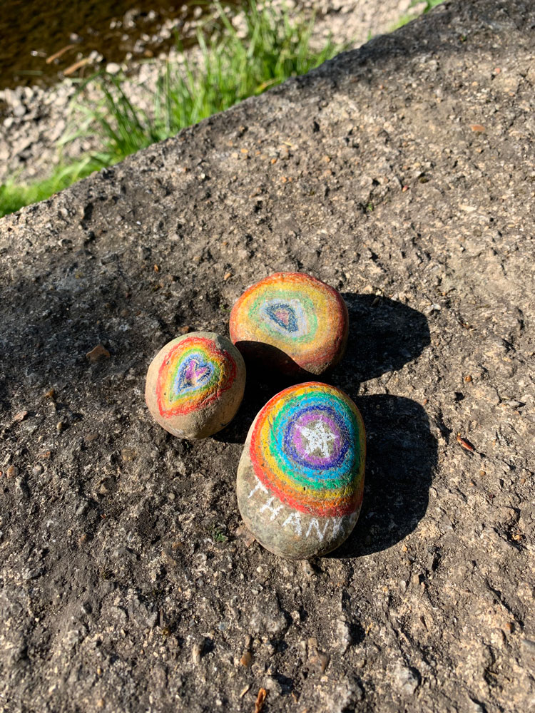 Three pebbles in the sunlight painted with rainbows
