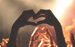 hands held high at a festival doing the mobot heart shape