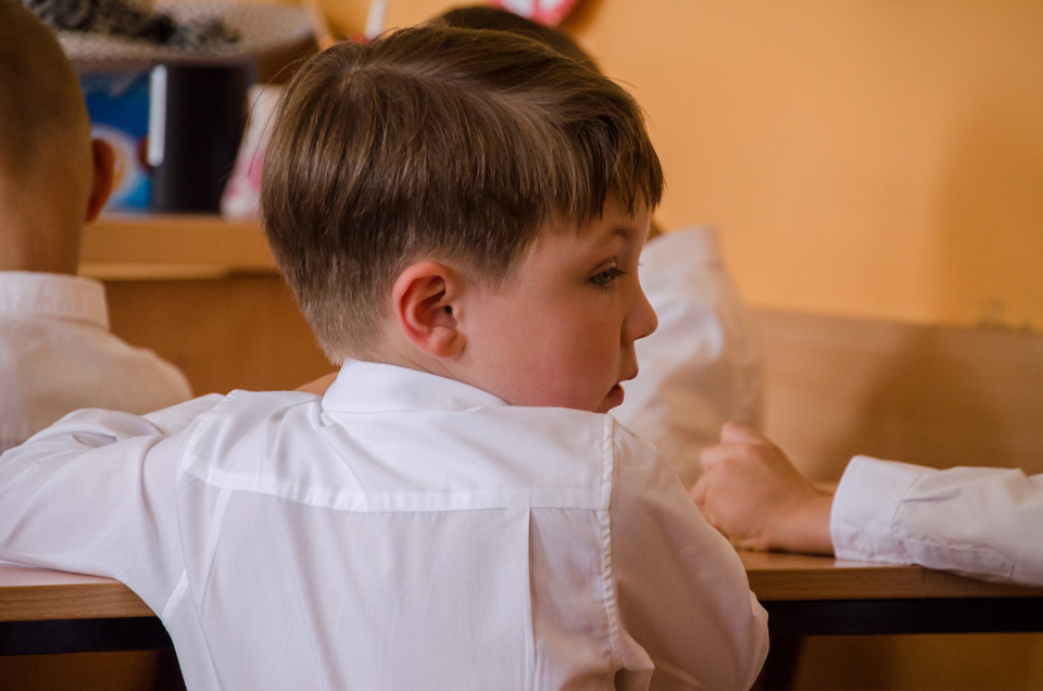 Boy sitting at a desk looking behind him