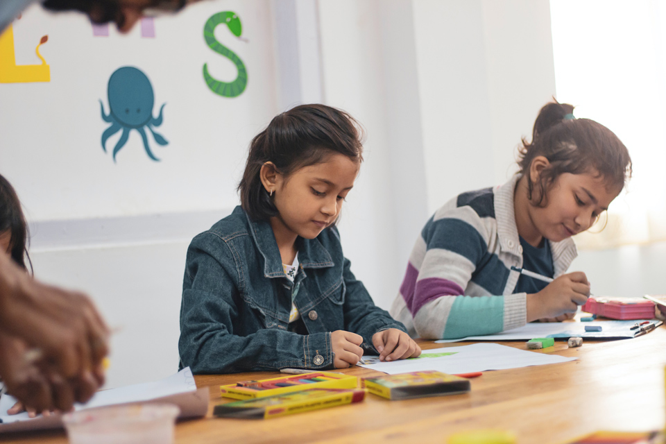 Two young girls sitting at a table working