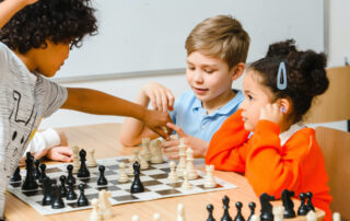 three children getting excited playing chess