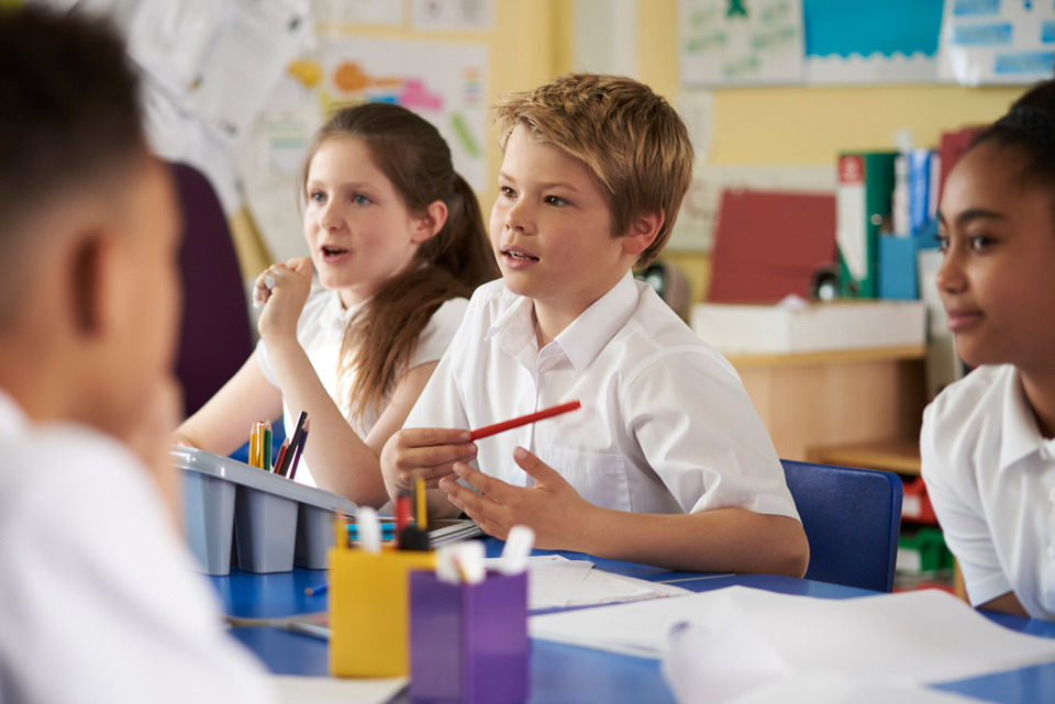 primary children sitting discussing at a table