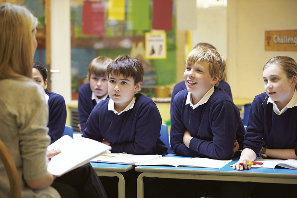 teacher sitting in front of pupils in uniform