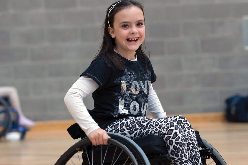 Happy girl in a wheelchair in a sports hall