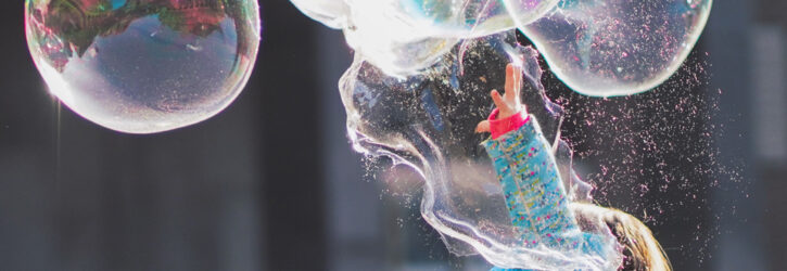 Young child bursting a soap bubble