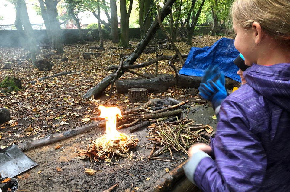 Girl looking at a fire just been started by her at Lea Green Centre, Let's Explore Day, October 2021