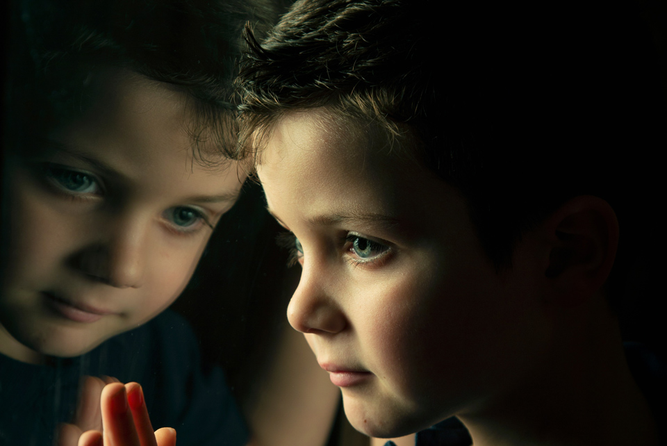 boy looking at his reflection in the window