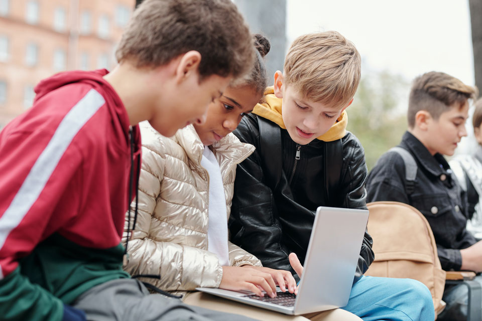 teenagers outside sitting working on a computer