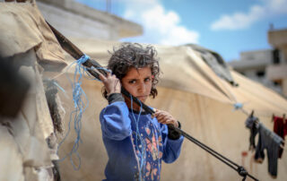 refugee child looking sad holding onto a tent rope