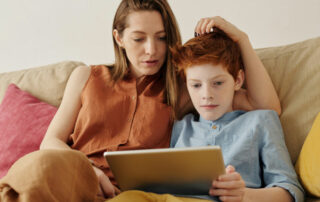 mother and child sitting on sofa looking at tablet