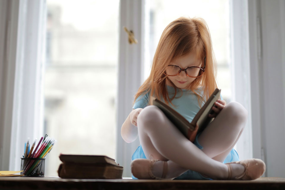 Girl in Blue Dress sitting crosslegged reading