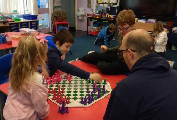 children and a parent taking part in four sided chess