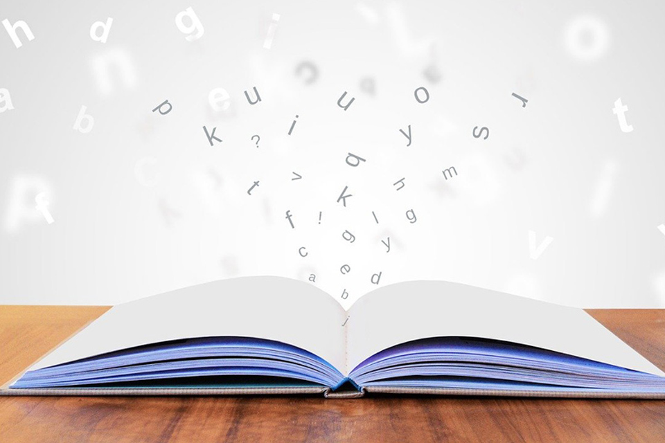 book lying open with letters jumping magically out of it