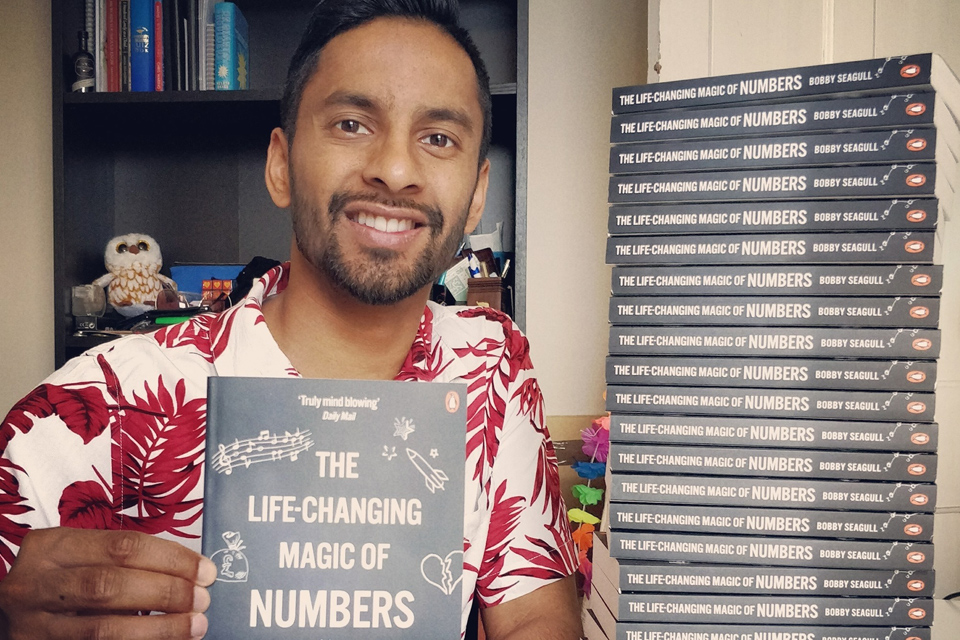 Bobby Seagull holding a copy of his book The Life-Changing Magic of Numbers