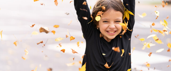 happy young girl throwing leaves into the air