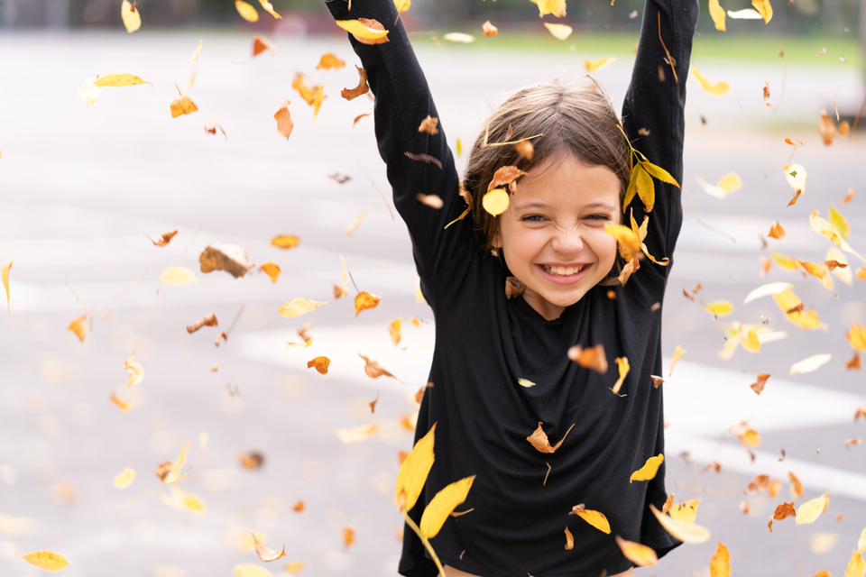 happy young girl throwing leaves into the air